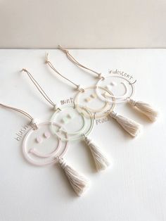 three white earrings with tassels hanging from them on top of a table next to each other