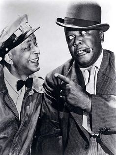 two men in hats are talking to each other while one man is pointing at the camera