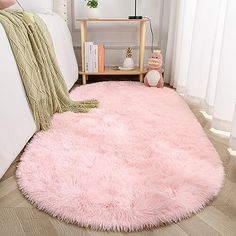 a pink rug is on the floor next to a white bed with pillows and a teddy bear