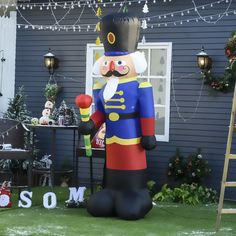 a large inflatable nutcracker standing next to a christmas decoration on the lawn