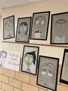 some drawings are hanging on the wall in front of people's heads and faces