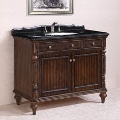 a bathroom vanity with black marble top and dark wood finish, in front of a white wall