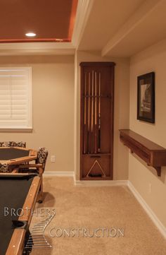 a pool table in the middle of a room with an entertainment center on either side