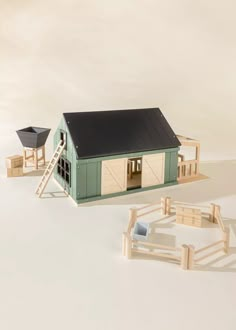 a toy house with a ladder to the roof next to it and a small wooden horse stable