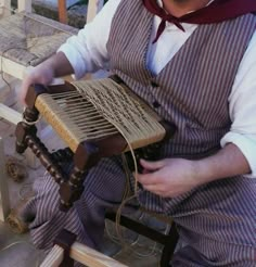 a man sitting on a chair holding an old fashioned wooden instrument in his right hand