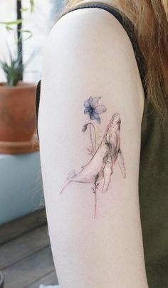 a woman with a tattoo on her arm holding a flower in one hand and a butterfly in the other