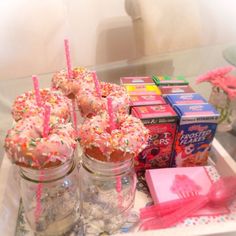 there are many donuts on the table with pink candles and candy sticks in them