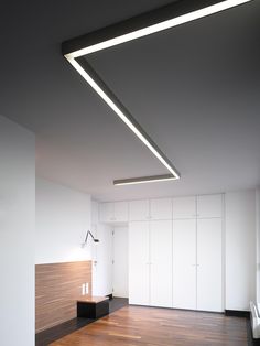 an empty room with white walls and wooden floors is lit by recessed light fixtures