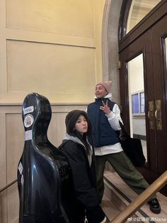 two people standing on the stairs in front of a door and talking to each other