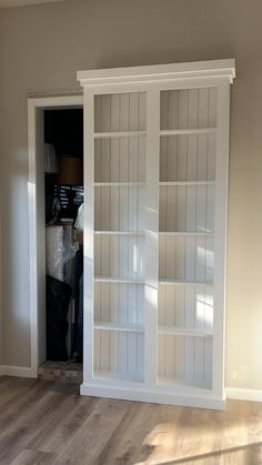 a large white bookcase sitting in the middle of a living room next to a doorway