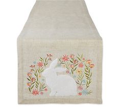 an embroidered table runner with a white rabbit and flowers on it