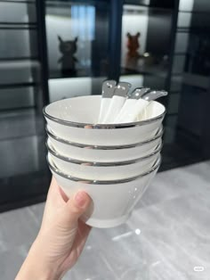 a hand holding a stack of white dishes