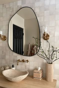 a bathroom with a sink, mirror and vase on the counter in front of it