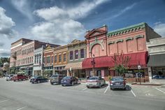 several cars are parked on the street in front of shops and businesses along with other buildings