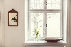 a vase with flowers in it sitting on a window sill next to a radiator