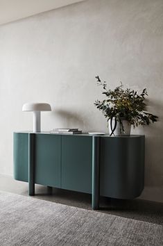 a plant is sitting on top of a sideboard next to a lamp and vase