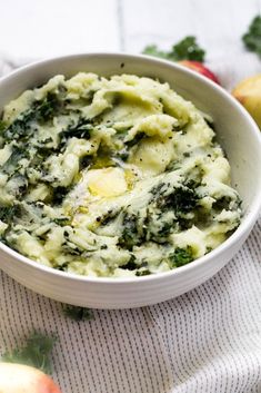 a white bowl filled with mashed potatoes and spinach on top of a table