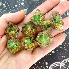 a hand holding five green and gold colored dices