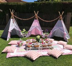 an outdoor picnic setting with pink and white checkered pillows, plaid tablecloths and teepee tents