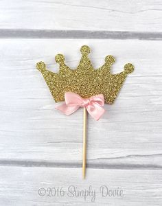 a cake topper with a pink bow on it and a gold crown on it