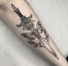 a black and white photo of a knife with flowers on the side of her leg