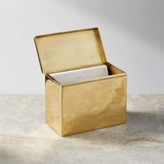 an open gold box on a table with a notepad in it's lid