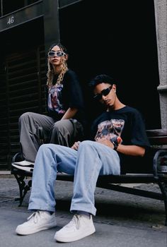 two people sitting on a bench in front of a building