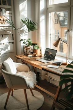 a laptop computer sitting on top of a wooden desk in front of a large window