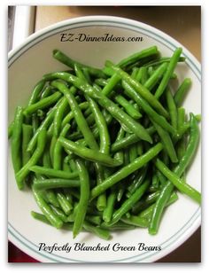 a white bowl filled with green beans on top of a table