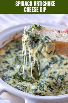 a hand holding a piece of bread over a bowl of spinach dip