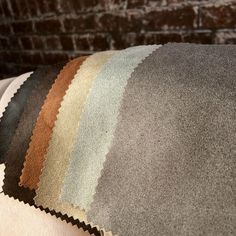 several different colors of fabric on top of each other in front of a brick wall