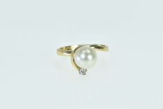 14K Cultured Pearl Diamond Ornate Curvy Vintage Ring Size 5.25 Yellow Gold *Weight: 2.9g *Center Gem Stone: 7.8mm Cultured Pearl *Gemstones: 1x=Diamond   *Composition: 14k Gold Marked *Condition: Estate:Good *Ring Size: 5.25 *Era: Vintage Estimated Retail Replacement Value: $749.99 Please note: Unless otherwise noted, our items are solid gold (i.e. if it is listed as 14K Gold, it means it is solid 14K, not gold plated). Where applicable, all diamonds are graded according to GIA grading standards Pearl Gemstone, Pearl Diamond, Vintage Ring