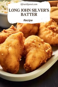 a white plate topped with fried food next to a bowl of cole slivers