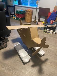 a cardboard airplane sitting on top of a hard wood floor