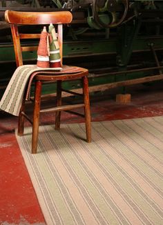 a wooden chair with an orange and white striped blanket on it next to a green machine