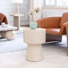 a living room filled with furniture and a vase on top of a small round table