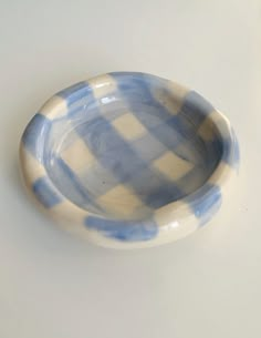 a blue and white checkered bowl sitting on top of a table next to a wall