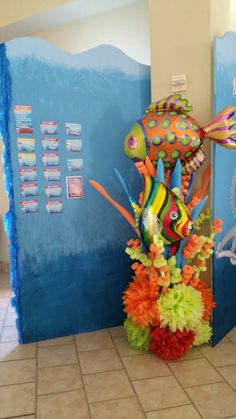 a colorful fish sculpture in front of a blue wall and tiled floor with tile floors