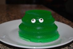 a green cake with googly eyes sitting on a white plate