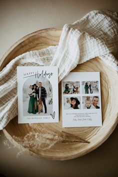 two wedding cards on top of a wooden bowl next to a white blanket and a couple's photo