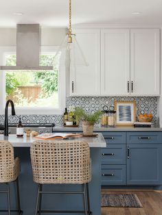 a kitchen with blue cabinets and wicker chairs in the middle of the countertop