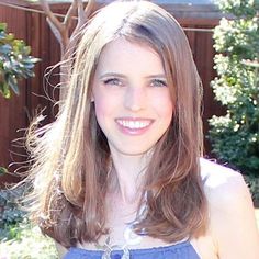 a woman in a blue dress smiling at the camera