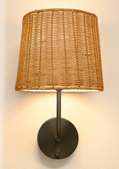 a lamp that is on the wall with a wicker shade