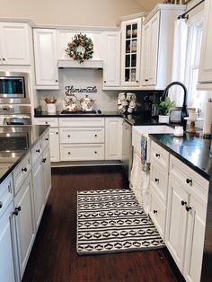 a kitchen with white cabinets, black counter tops and an area rug on the floor