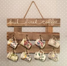 a wooden sign with coffee mugs hanging from it