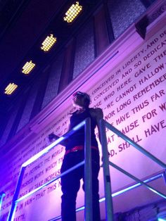 a woman standing on top of a metal railing next to a wall with words written on it