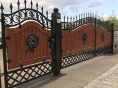 an iron gate with two clocks on it and a brick walkway next to the fence