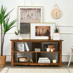 a wooden shelf with books and pictures on it next to a potted palm tree