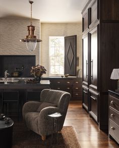 a modern kitchen with dark wood cabinets and black counter tops, along with a gray chair in the center