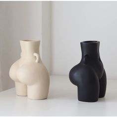 two vases sitting next to each other on a white countertop in front of a window